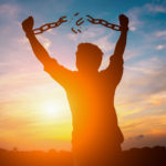 silhouette image of a businessman with broken chains in sunset