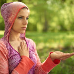 portrait of beautiful mixed race caucasian, african, middle eastern girl meditating and doing yoga at sunset on the grass in a park or forrest