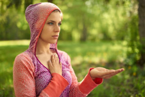 portrait of beautiful mixed race caucasian, african, middle eastern girl meditating and doing yoga at sunset on the grass in a park or forrest